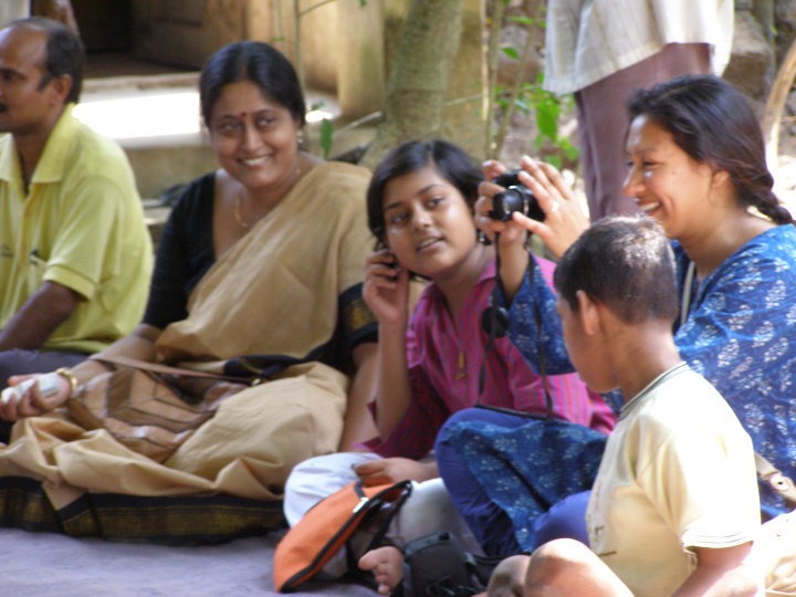 Rubayi sitting among others taking photos -Evaluating Community Engagement