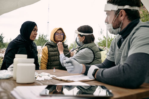 Disaster Relief team with face masks holding medical consultations for migrants